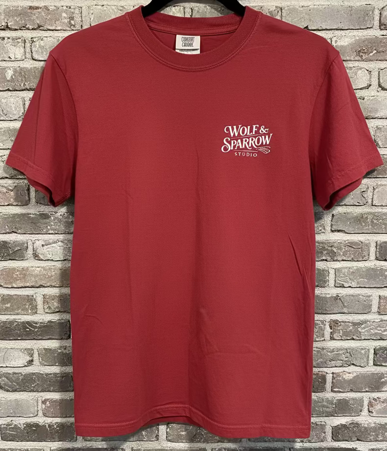 A chili t-shirt with the logo Wolf & Sparrow Studio in black against a grey brick background