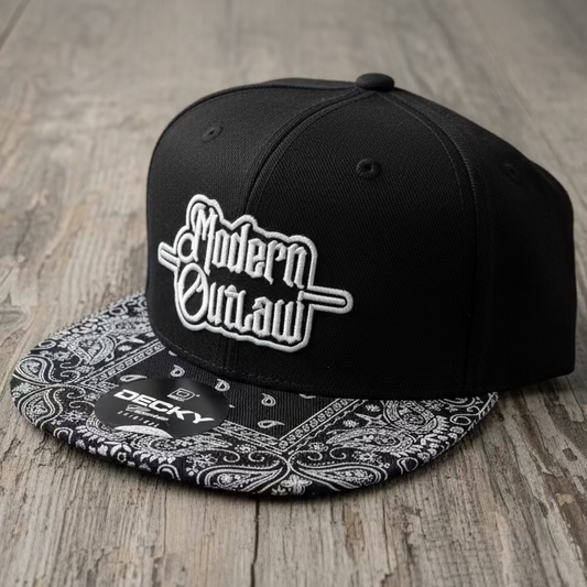 A black snapback with a black and white paisley bill and a 3D embroidery patch that says "Modern Outlaw" on a neutral grey background