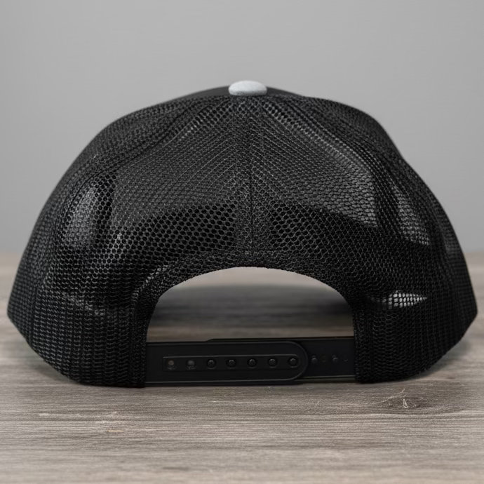 The back mesh of a black snapback with black adjustable straps on a rustic style table with grey neutral colors