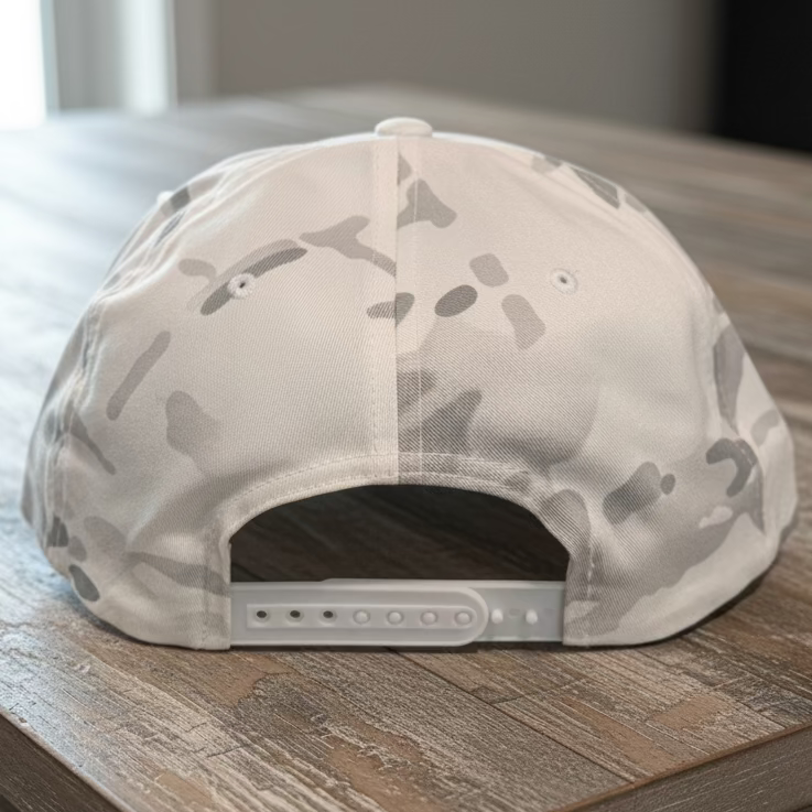 The back of a white forest camo snapback on a rustic style table with neutral colors