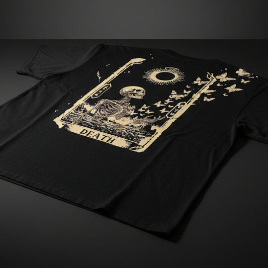 The back of a black pocketed t-shirt with a design of a death tarot card that shows a skeleton turning into butterflies and a new moon radiating against a black background