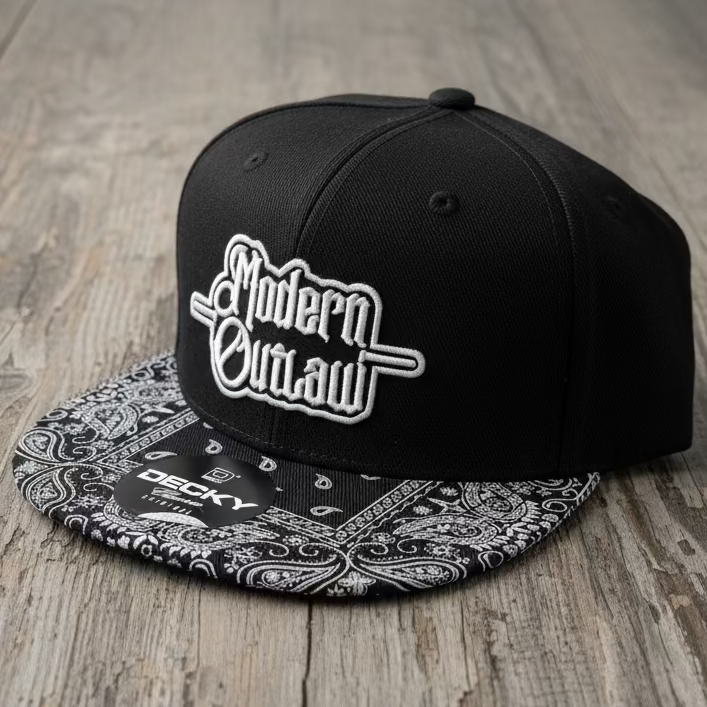 A black snapback with a black and white paisley bill and a 3D embroidery patch that says "Modern Outlaw" on a neutral grey background