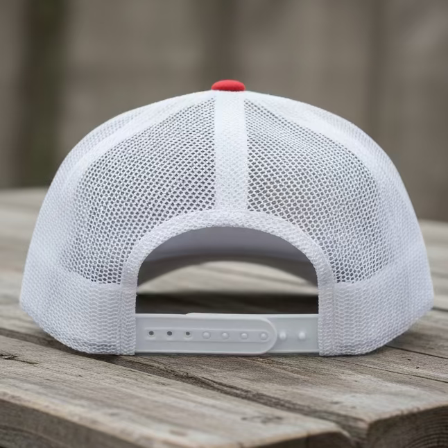 The back of a white snapback with a white trucker mesh backing on a rustic grey color table