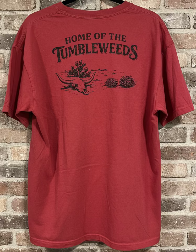 The back of a red t-shirt that says "Home of the Tumbleweeds" with a longhorn skull, cactus, and tumbeweeds. against a grey neutral background